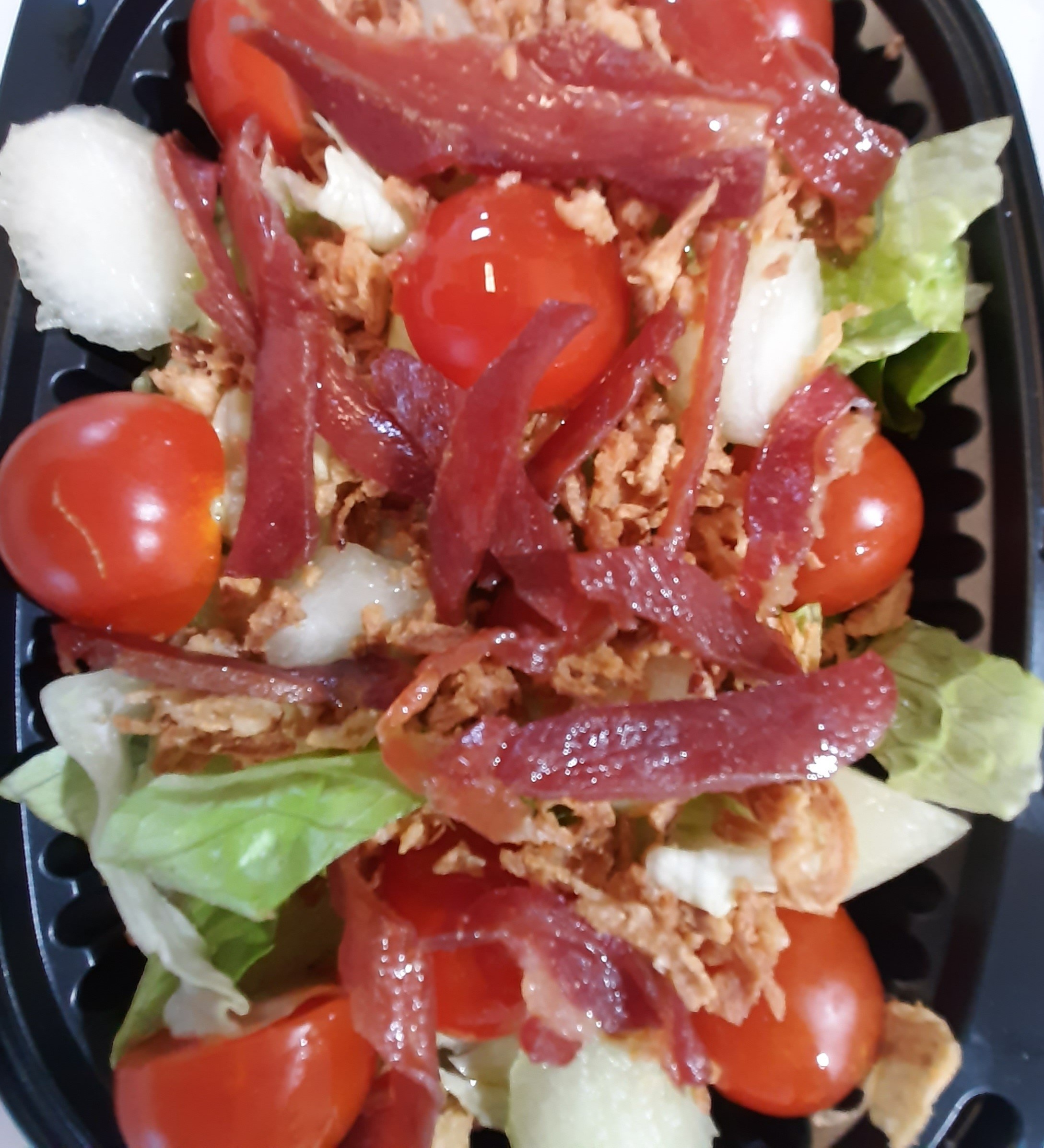 Ensalada de brotes, perlas de melón, cherry, jamón y cebolla crujiente.