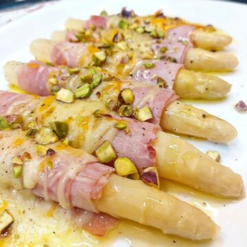 Espárragos blancos gratinados con bacon, queso y pistachos.