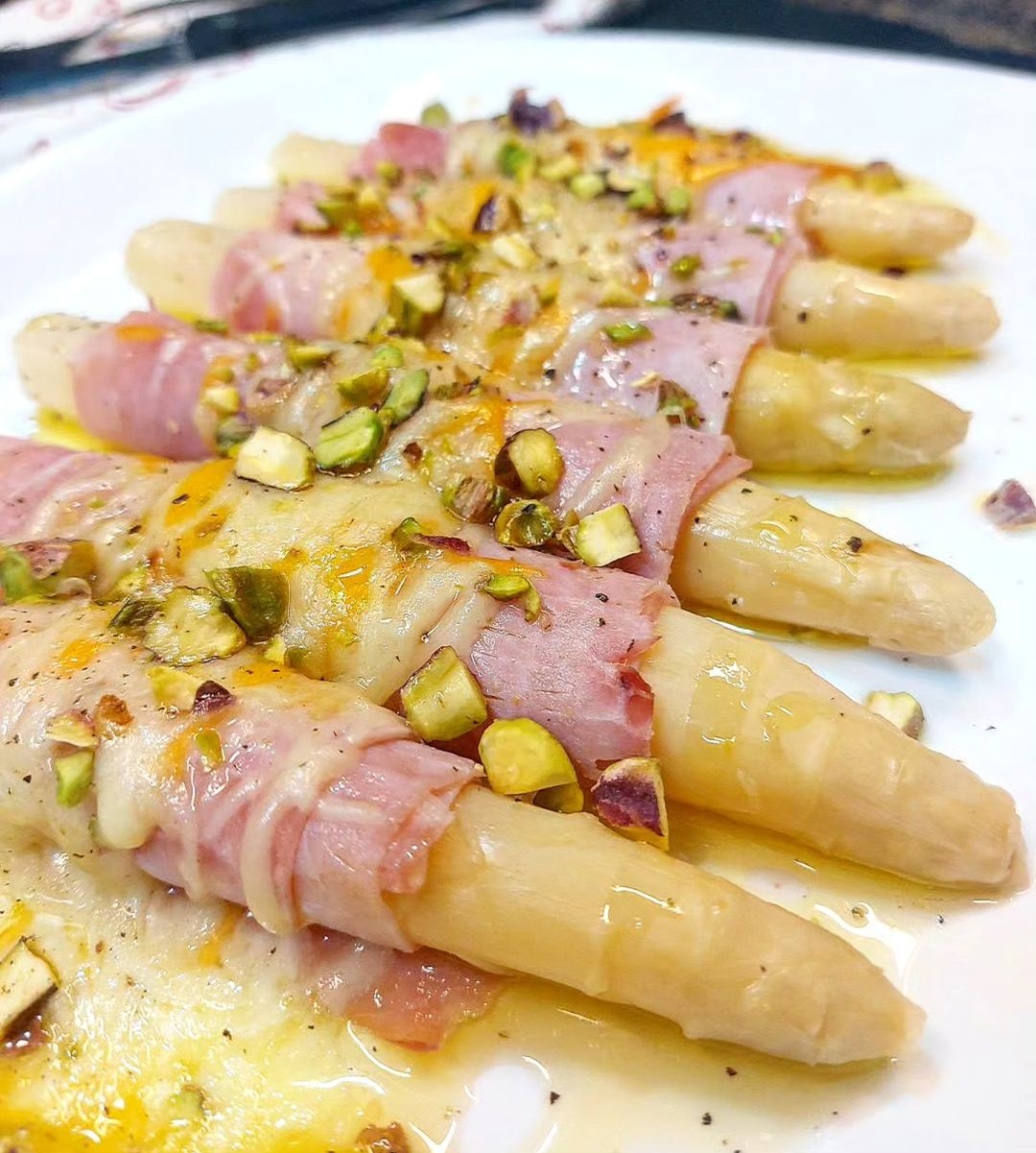 Espárragos blancos gratinados con bacon, queso y pistachos.